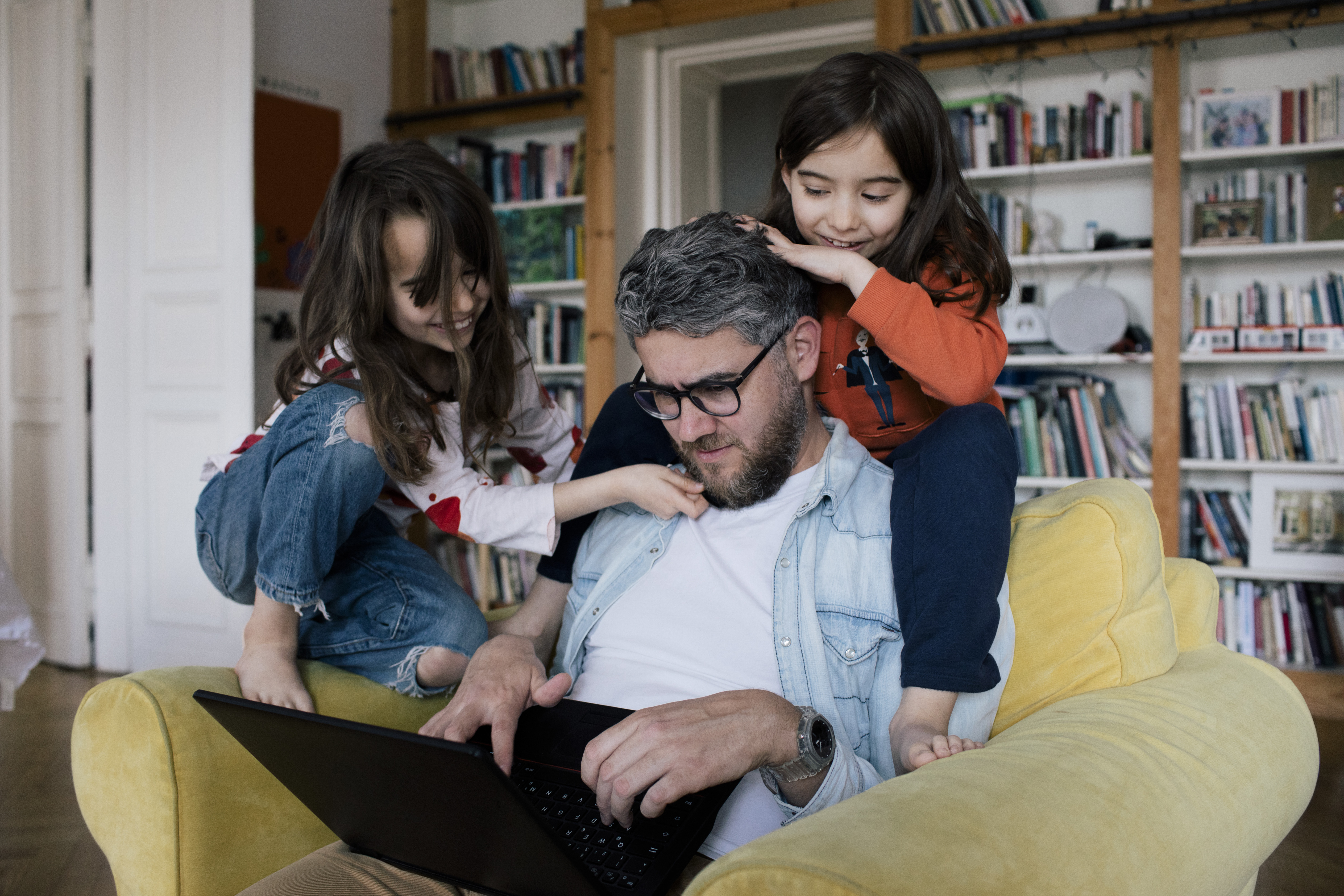 Dad looking at a laptop together with his kids