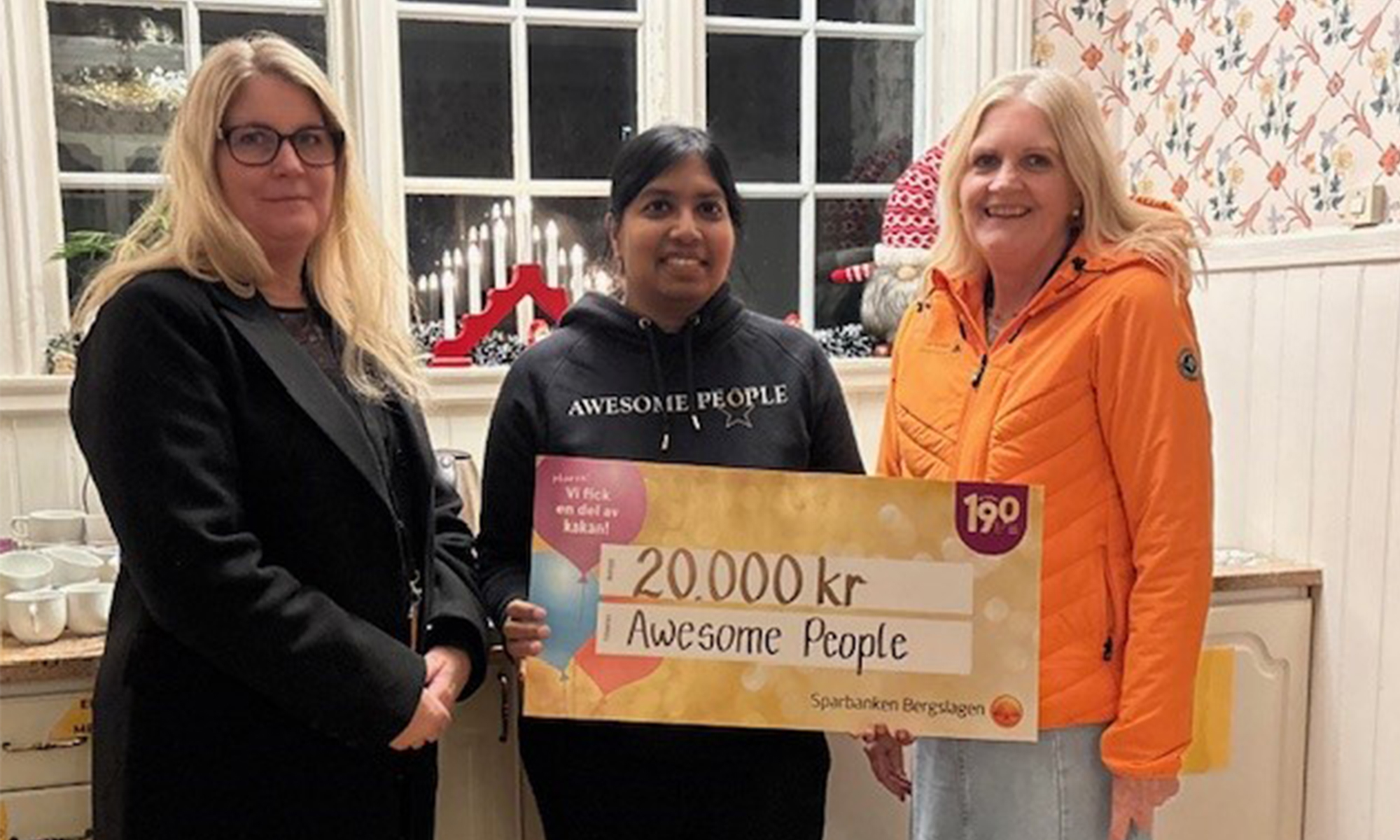 Personer från Awesome People håller upp en värdecheck på 20 000 kr.