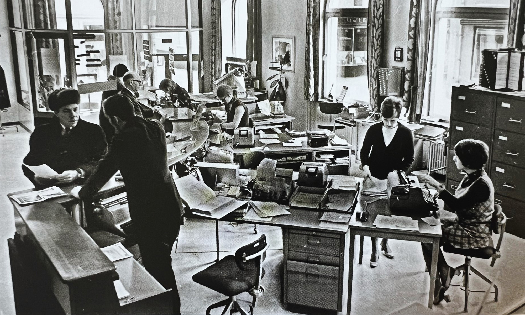 Äldre svartvitt foto från 1900-talets andra hälft av kontorsmiljö från Noras sparbank.