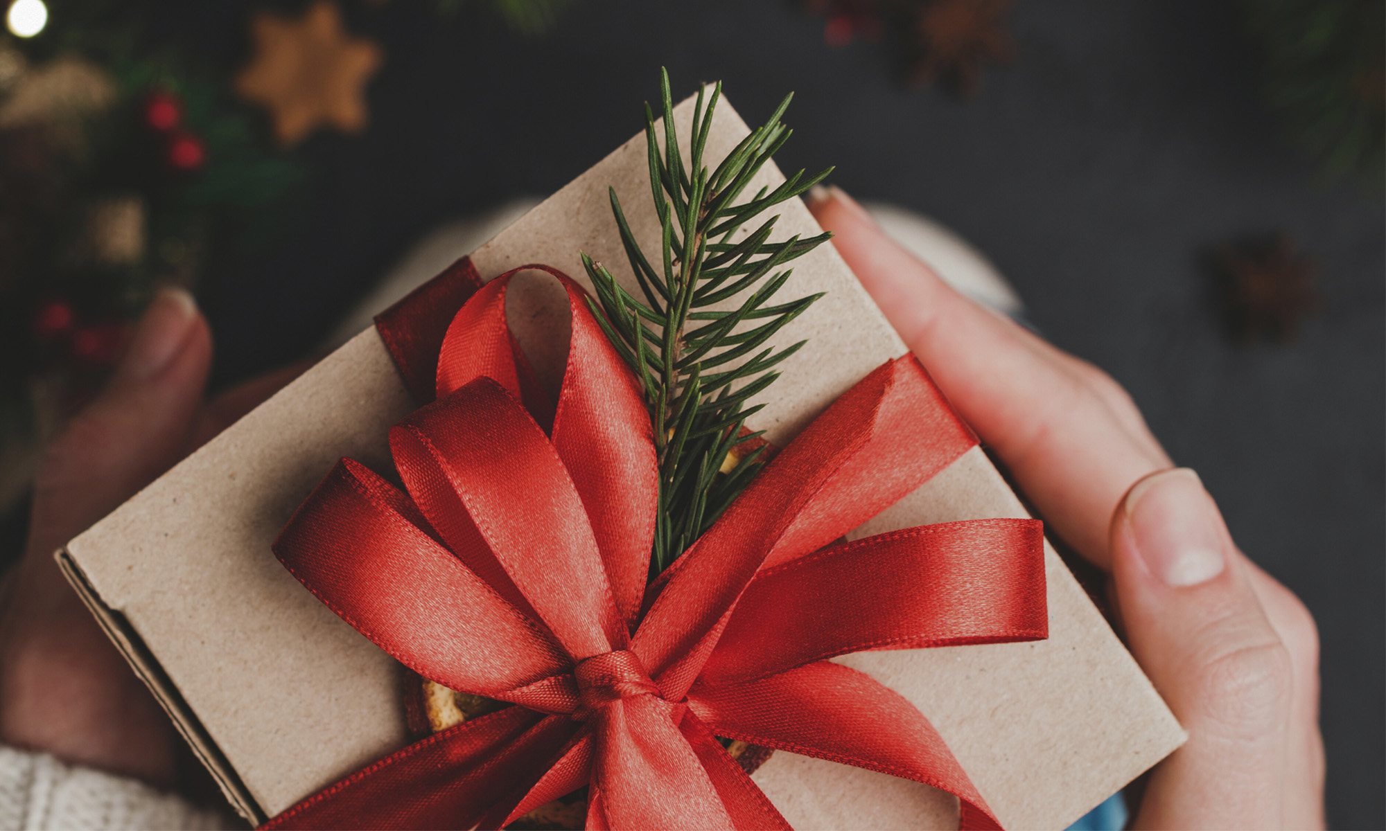 Närbild två händer som håller i ett litet paket med röda snören.