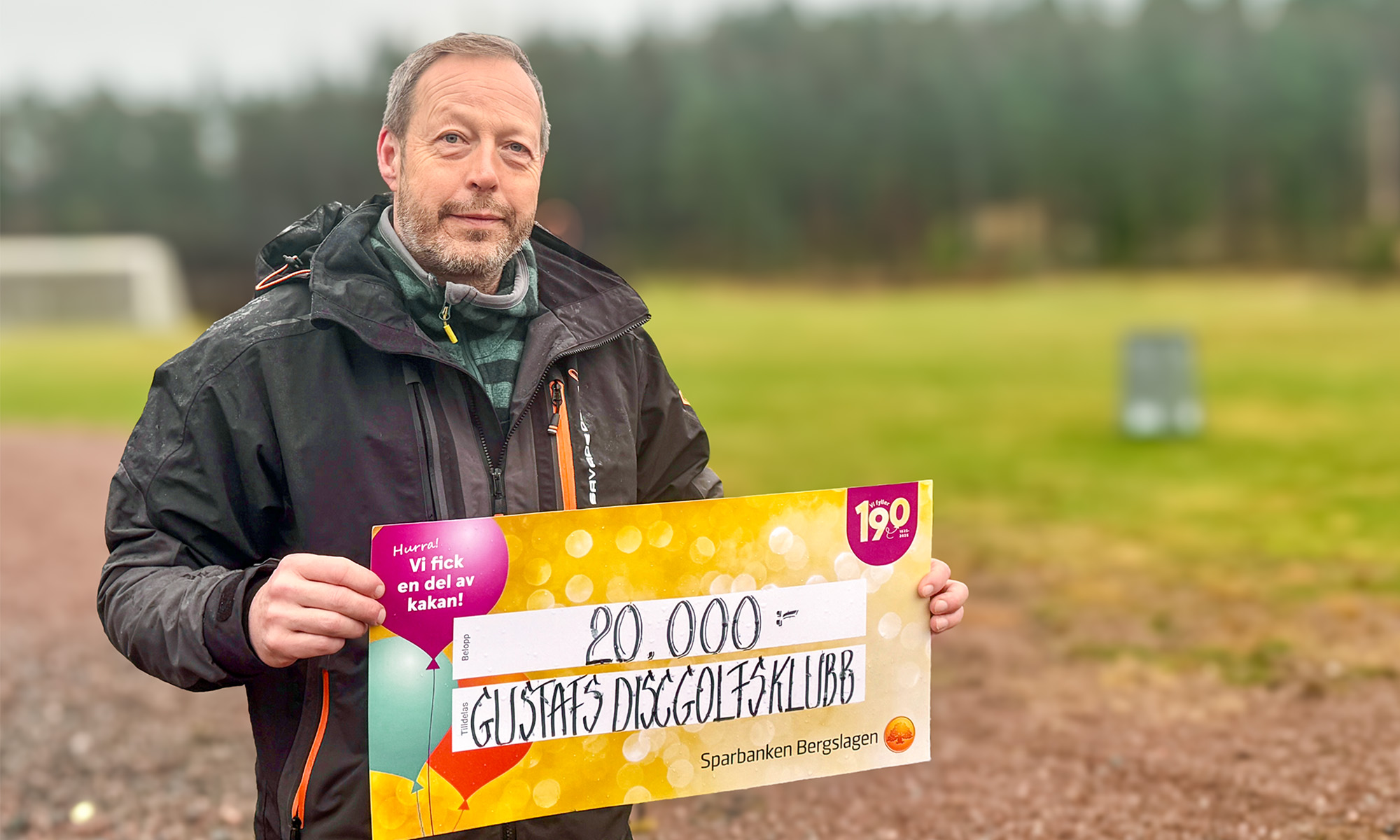 En man visar upp vinnarchecken på 20 000 kr.