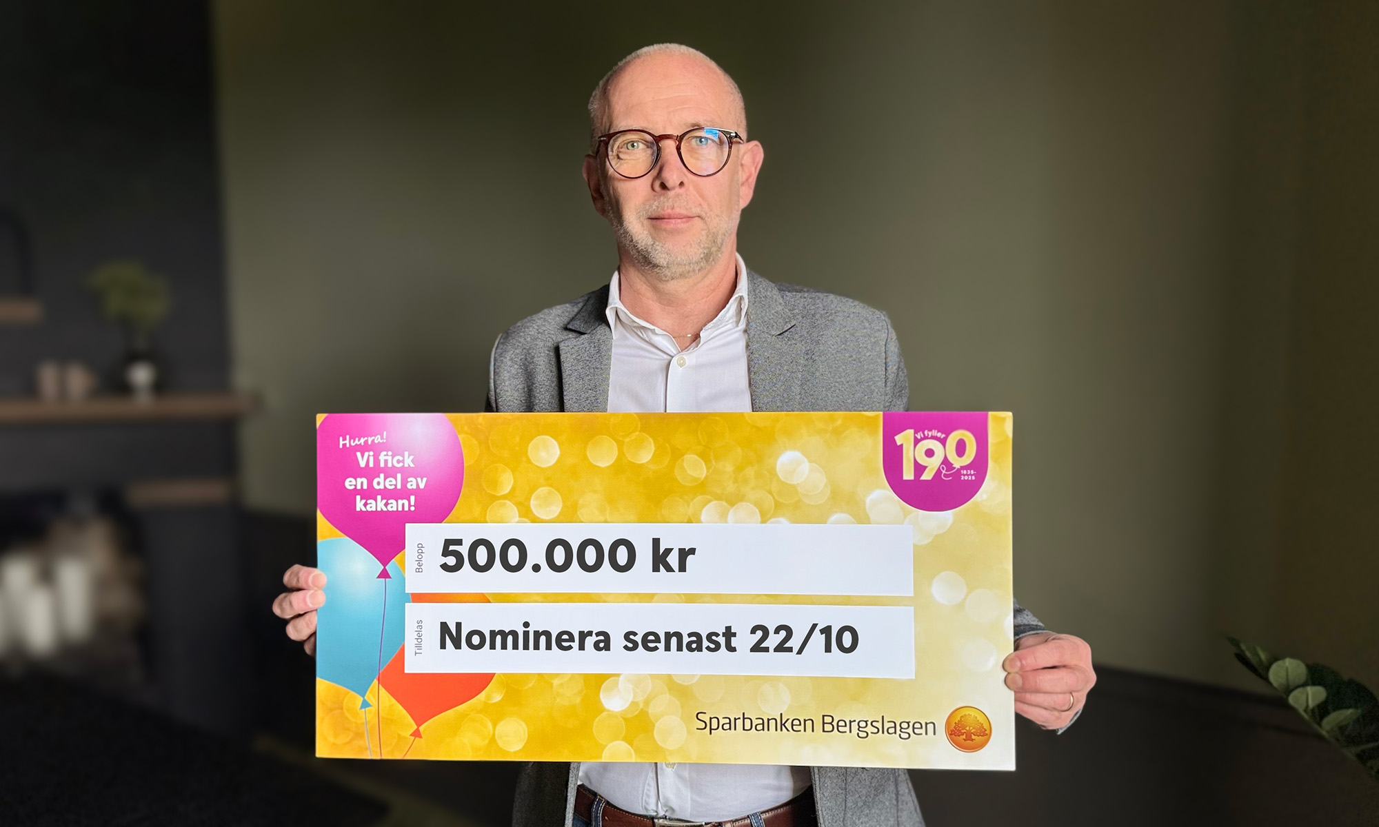 VD Jonas Nyberg står och håller upp en stor check där det står 500 000 kr samt Nominera senast 22/10