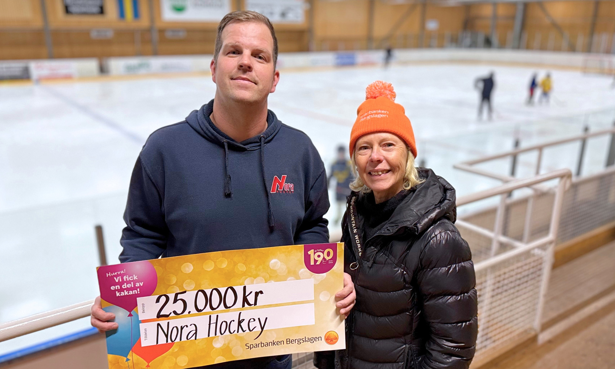 En man från Nora Hockey håller upp sin värdecheck på 25 000 kr