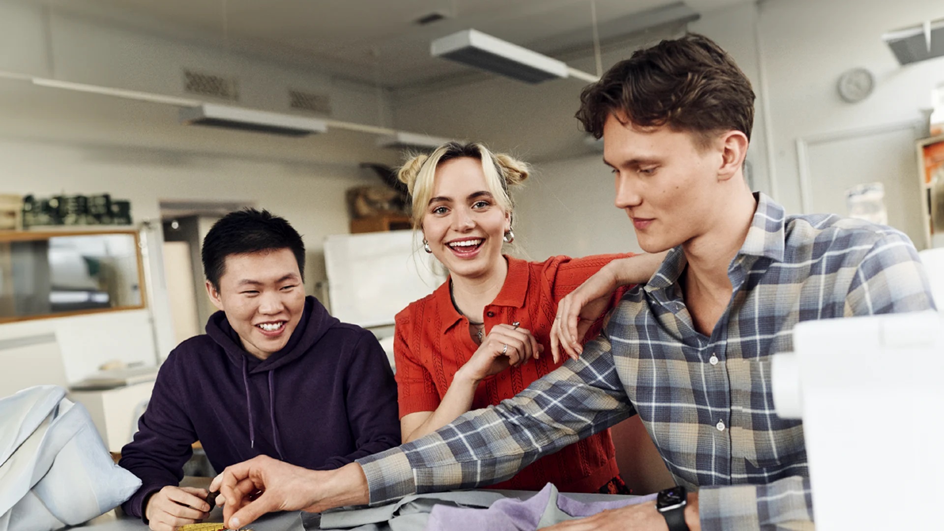 Three students sewing in a classroom
